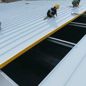 Κλίση στέγης με πάνελ: τοποθέτηση πάνελ πολυουρεθάνης σε στέγη με κλίση — τεχνίτες στερεώνουν μεταλλικά φύλλα σε κατασκευή οροφής