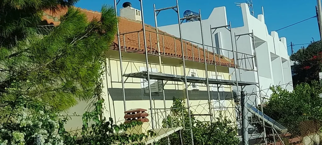 Σκαλωσιές γύρω από το σπίτι για την τοποθέτηση πάνελ κεραμίδι στη στέγη.