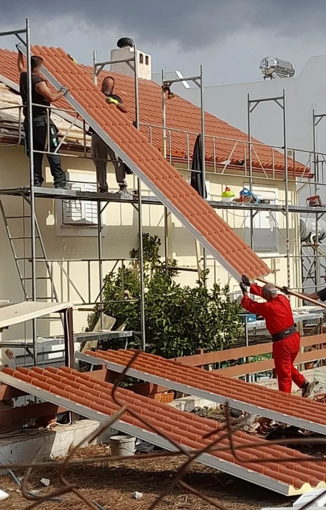 Εργάτες τοποθετούν πάνελ κεραμίδι στη στέγη κατοικίας.